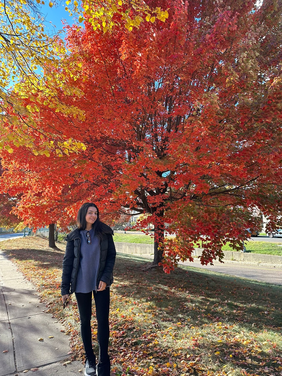 Iqra Nadeem standing beneath a red autumn tree